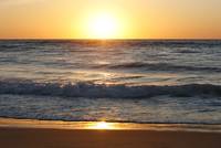 A golden sunset frames the silver-grey ocean